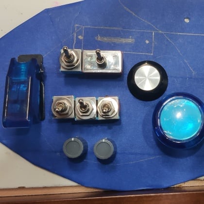 the back of a Ric pickguard with blue painters' tape with outlines marked in pencil and controls laid out on top